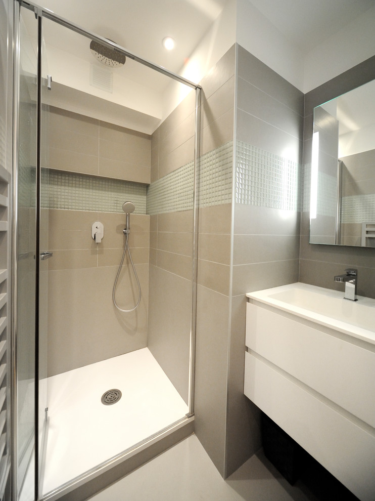 Cette image montre une petite salle de bain principale design avec un placard à porte plane, des portes de placard blanches, une baignoire encastrée, une douche à l'italienne, un mur beige, un sol gris et une cabine de douche à porte battante.