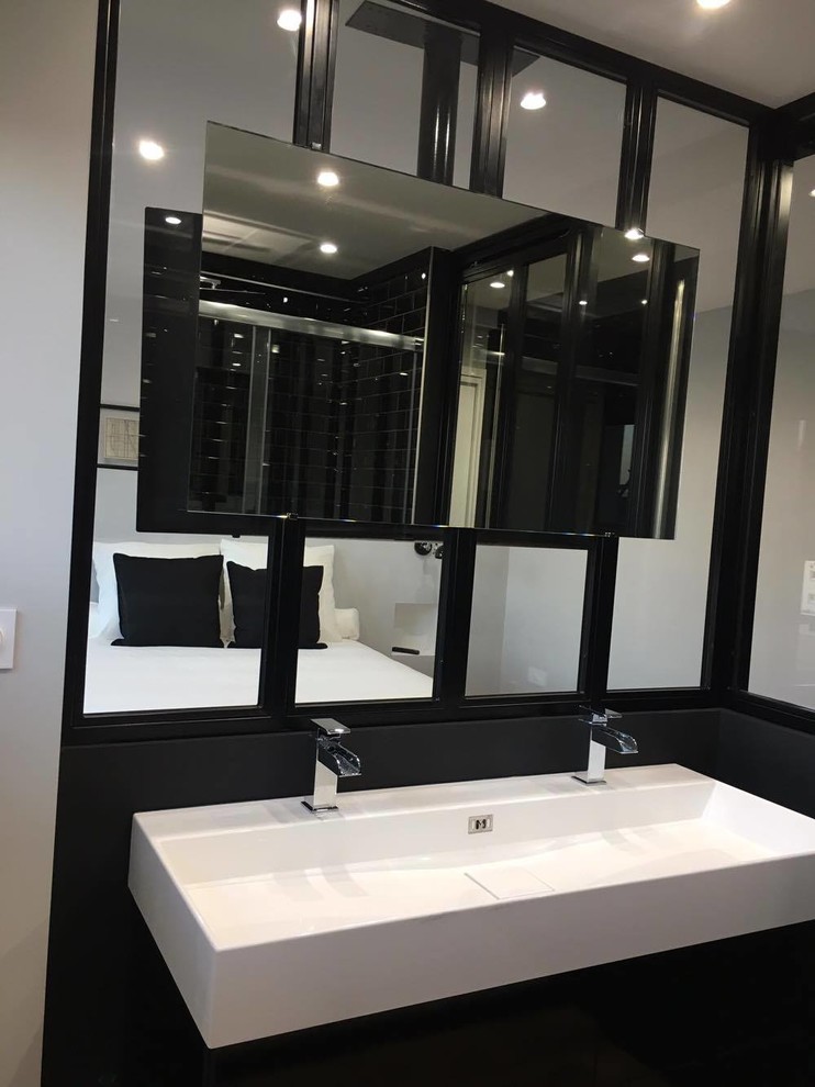 Immagine di una piccola stanza da bagno con doccia moderna con ante nere, doccia a filo pavimento, WC sospeso, piastrelle nere, piastrelle in ceramica, pareti grigie, pavimento in laminato, lavabo rettangolare e top in marmo