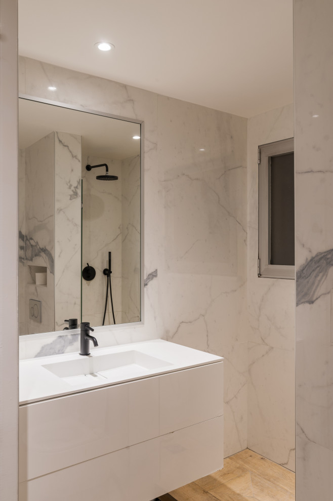 Photo of a medium sized contemporary ensuite bathroom in Paris with flat-panel cabinets, white cabinets, a wall mounted toilet, grey tiles, marble tiles, grey walls, light hardwood flooring, a wall-mounted sink, beige floors, white worktops, a single sink and a floating vanity unit.