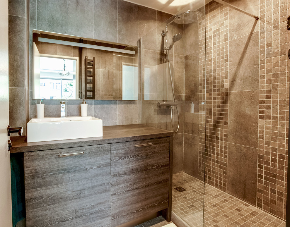 Ispirazione per una piccola stanza da bagno con doccia industriale con doccia a filo pavimento, piastrelle grigie, pareti grigie, pavimento in cemento, lavabo da incasso, top in legno e pavimento grigio