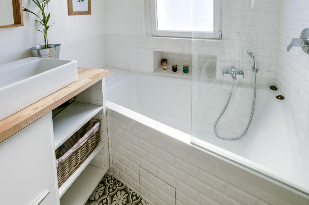 Imagen de cuarto de baño principal nórdico de tamaño medio con bañera encastrada sin remate, paredes blancas, suelo de azulejos de cemento, lavabo encastrado y encimera de madera