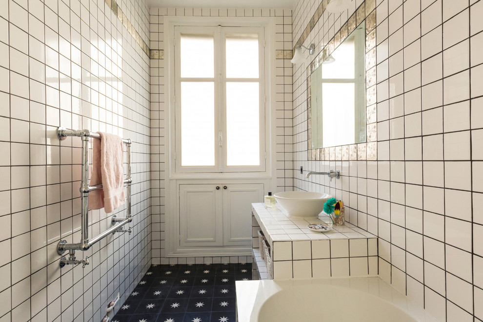 Klassisches Duschbad mit offenen Schränken, weißen Schränken, Einbaubadewanne, weißen Fliesen, Mosaikfliesen, weißer Wandfarbe, Aufsatzwaschbecken, gefliestem Waschtisch, schwarzem Boden und weißer Waschtischplatte in Paris