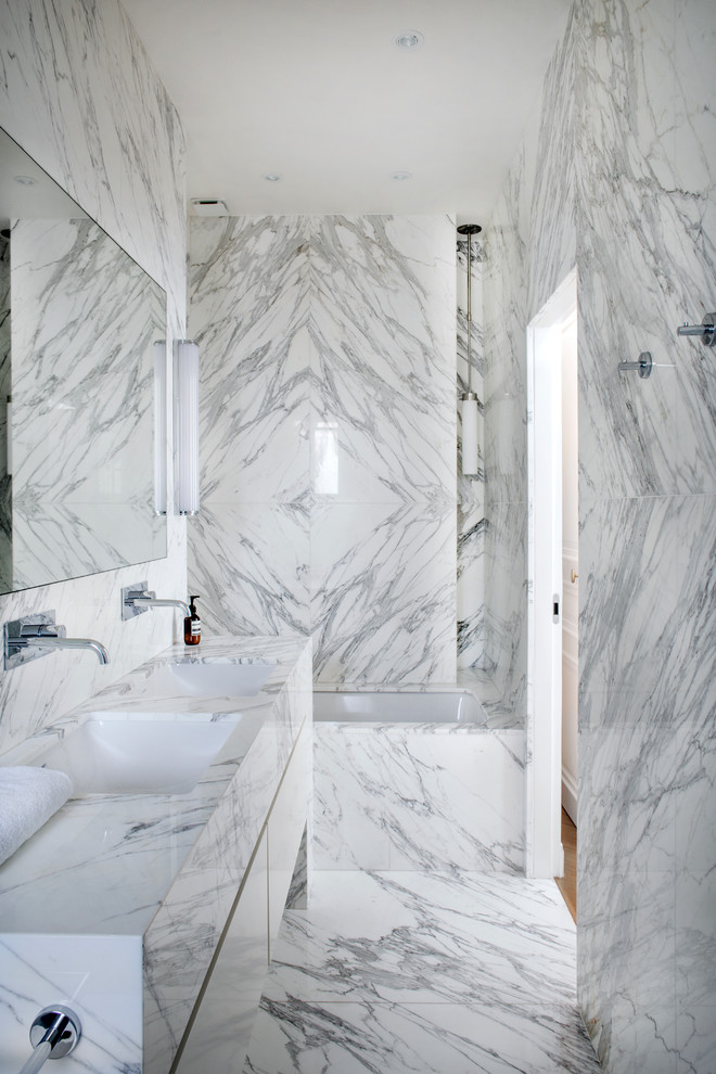 Modern inredning av ett en-suite badrum, med släta luckor, vita skåp, ett undermonterat badkar, ett undermonterad handfat, vitt golv, en dusch/badkar-kombination, grå kakel, marmorkakel, grå väggar, marmorgolv och marmorbänkskiva