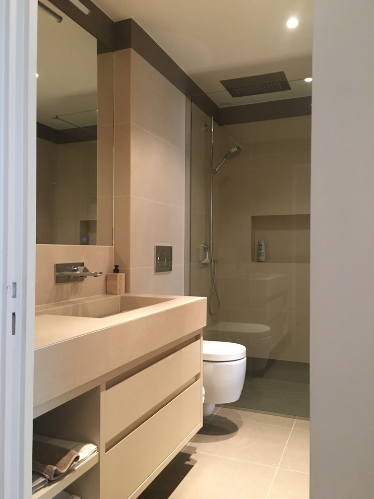 Idéer för små funkis beige en-suite badrum, med luckor med profilerade fronter, beige skåp, en kantlös dusch, en vägghängd toalettstol, beige kakel, keramikplattor, beige väggar, klinkergolv i keramik, ett integrerad handfat, kaklad bänkskiva, beiget golv och med dusch som är öppen