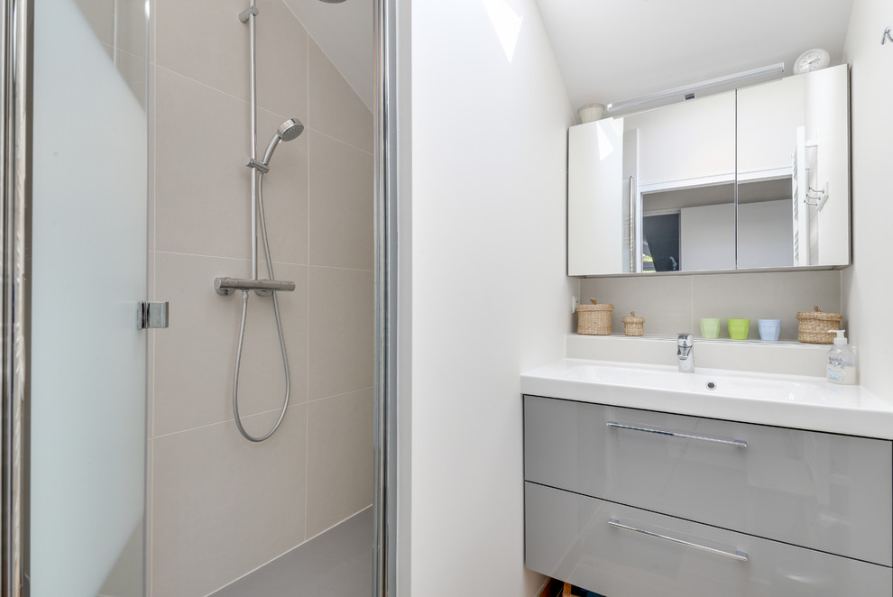 This is an example of a large traditional shower room bathroom in Paris with beaded cabinets, grey cabinets, a built-in shower, a wall mounted toilet, beige tiles, ceramic tiles, beige walls, ceramic flooring, a wall-mounted sink, solid surface worktops, a hinged door and white worktops.