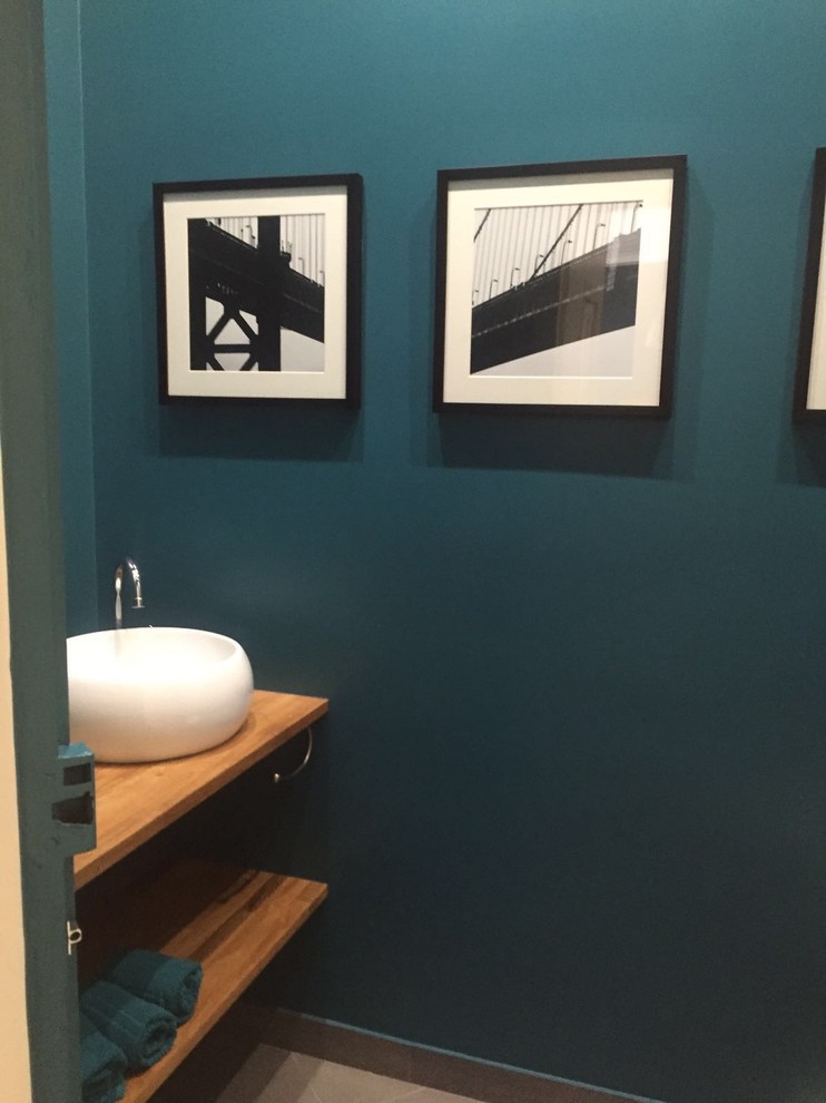 Cette photo montre une salle d'eau tendance de taille moyenne avec un mur bleu, carreaux de ciment au sol, un lavabo posé, un plan de toilette en bois et un sol gris.