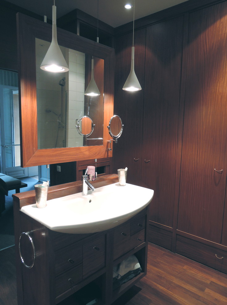 Réalisation d'une salle de bain design en bois foncé avec un placard à porte affleurante.