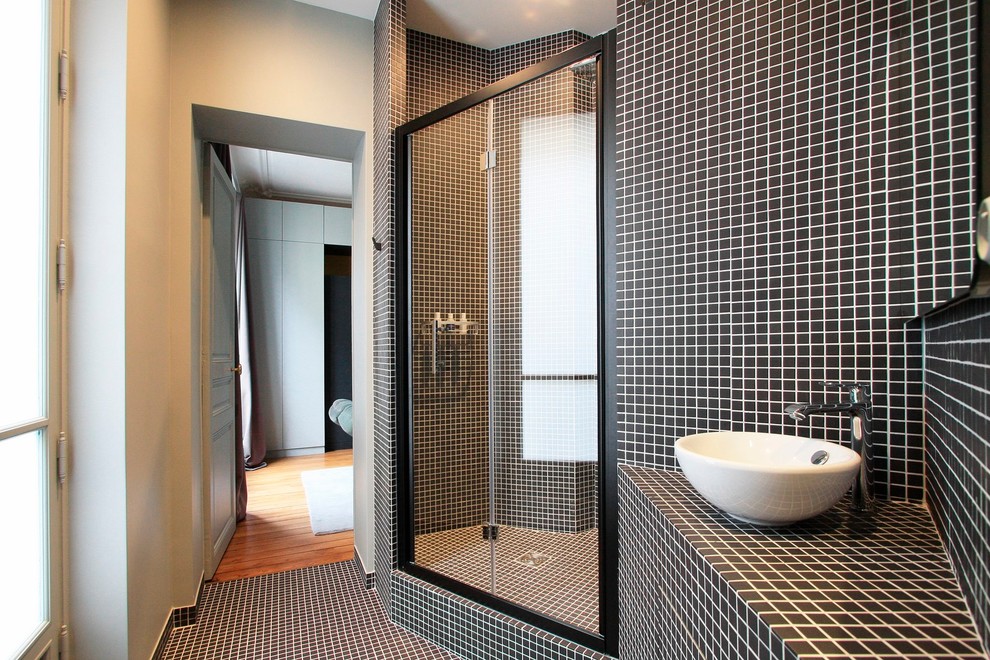 Foto på ett mellanstort funkis badrum med dusch, med ett fristående handfat, kaklad bänkskiva, en dusch i en alkov, svart kakel, mosaik, svarta väggar och mosaikgolv