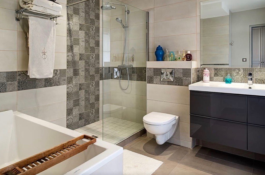 Cette photo montre une salle de bain principale rétro de taille moyenne avec une baignoire encastrée, une douche à l'italienne, WC suspendus, un carrelage beige, des carreaux de béton, un mur beige, un sol en carrelage de céramique, un plan vasque et un sol beige.