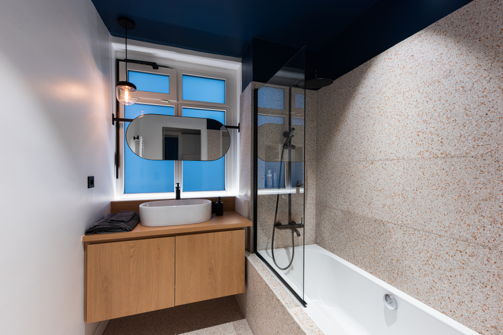 На фото: ванная комната среднего размера в современном стиле с плоскими фасадами, бежевыми фасадами, ванной в нише, душем над ванной, разноцветной плиткой, белыми стенами, полом из терраццо, душевой кабиной, настольной раковиной, разноцветным полом, открытым душем и бежевой столешницей