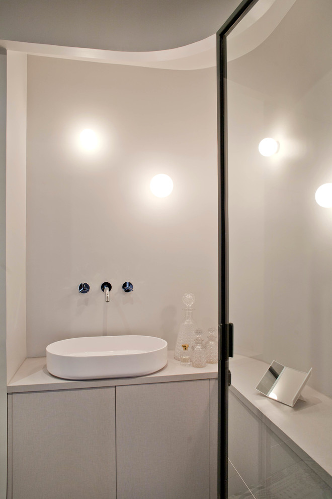 Exemple d'une salle de bain principale et grise et blanche tendance avec un placard à porte plane, des portes de placard grises, un mur blanc, une vasque, meuble simple vasque et meuble-lavabo encastré.