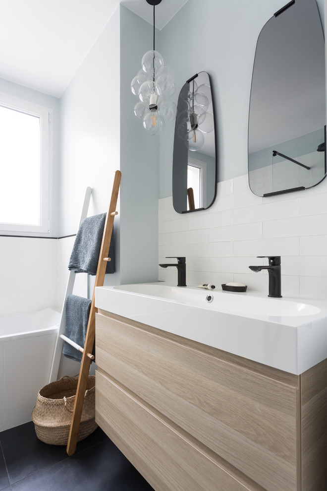 Design ideas for a medium sized scandi ensuite bathroom in Paris with a built-in bath, white tiles, flat-panel cabinets, light wood cabinets, metro tiles, black floors, a shower/bath combination, a two-piece toilet, white walls, ceramic flooring, a trough sink, solid surface worktops and white worktops.