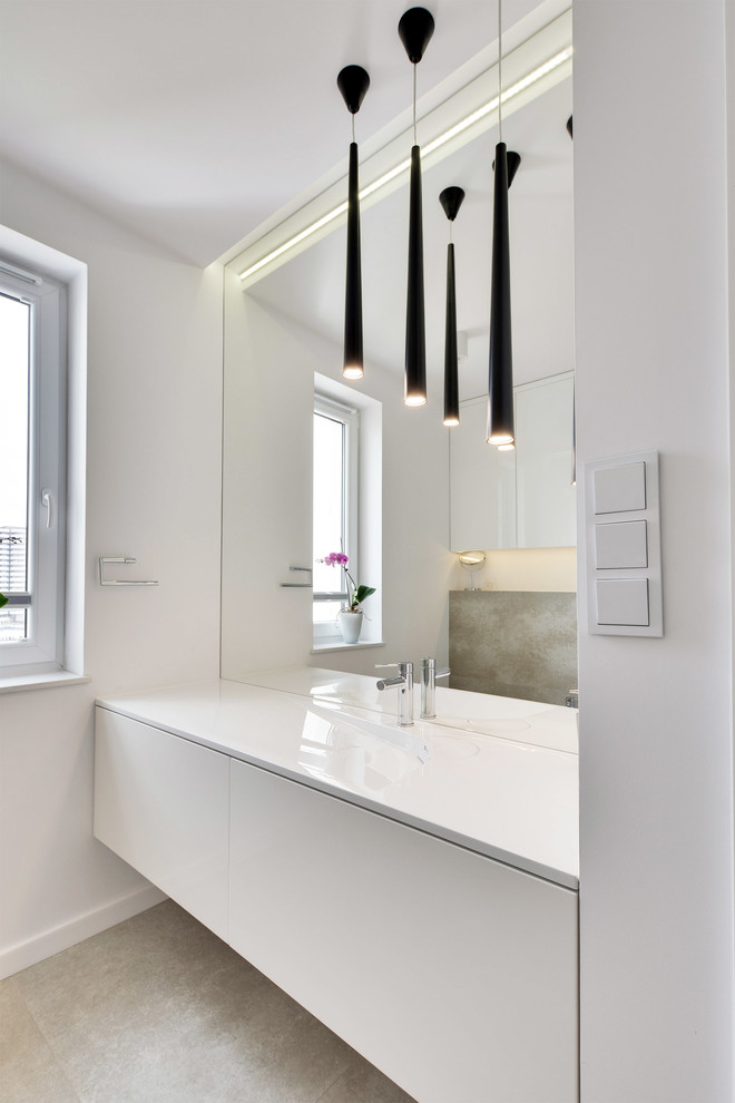 На фото: большая главная ванная комната в стиле модернизм с плоскими фасадами, белыми фасадами, белыми стенами, полом из известняка и монолитной раковиной с