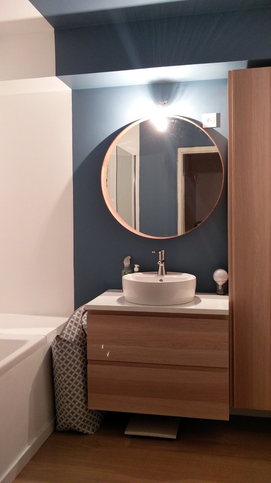 Réalisation d'une petite salle de bain principale nordique en bois clair avec une baignoire encastrée, un combiné douche/baignoire, un mur bleu, parquet clair et un lavabo posé.