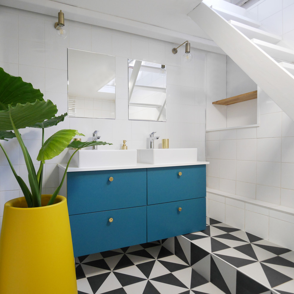 Exemple d'une salle de bain tendance avec un placard à porte plane, des portes de placard bleues, un carrelage blanc, un mur blanc, une vasque et un plan de toilette blanc.