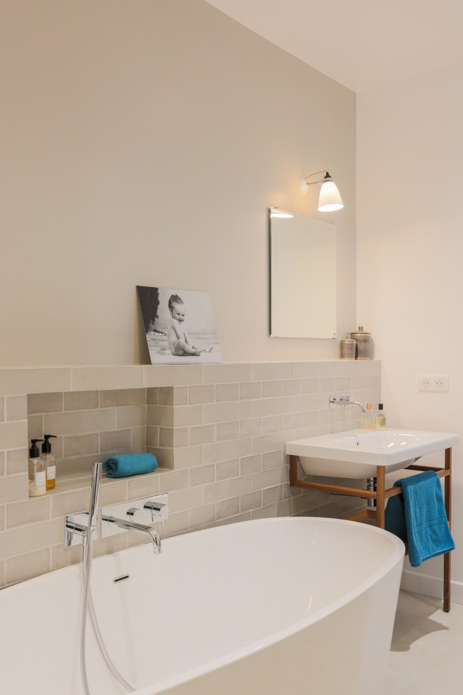 Immagine di una stanza da bagno con doccia minimal di medie dimensioni con vasca/doccia, pareti beige, pavimento beige, doccia aperta, vasca freestanding, piastrelle beige e lavabo sospeso