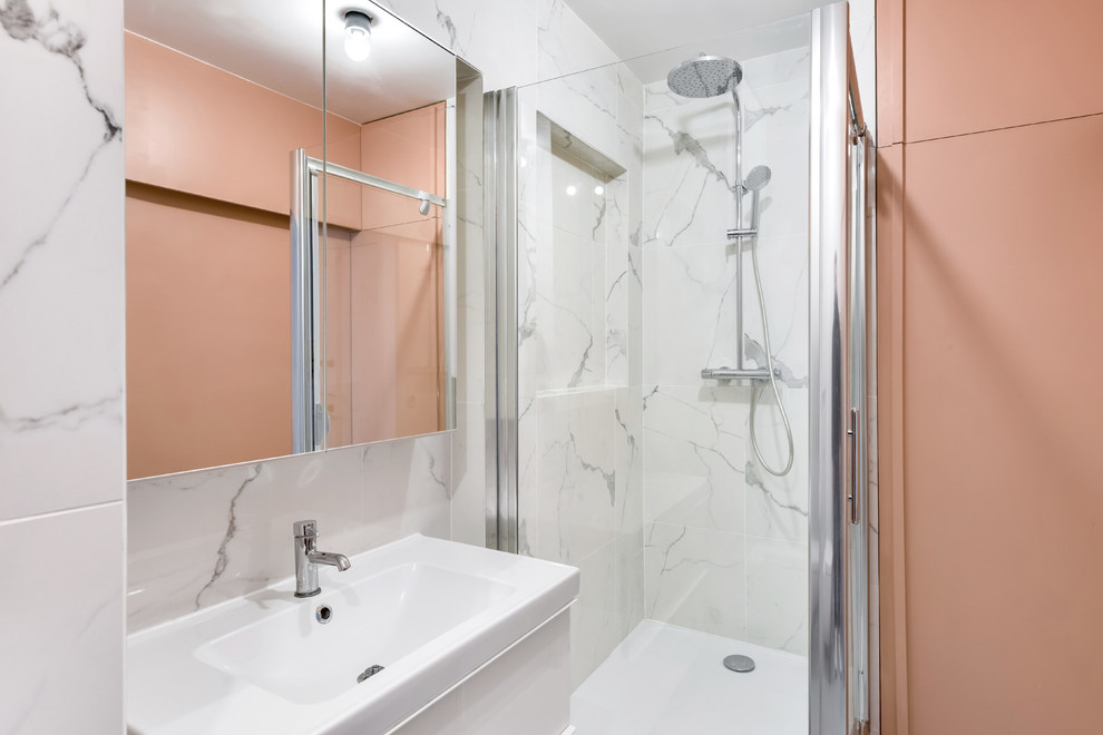 Cette image montre une salle de bain design avec un placard à porte plane, des portes de placard blanches, une douche d'angle, un carrelage blanc, un mur rose et un plan vasque.