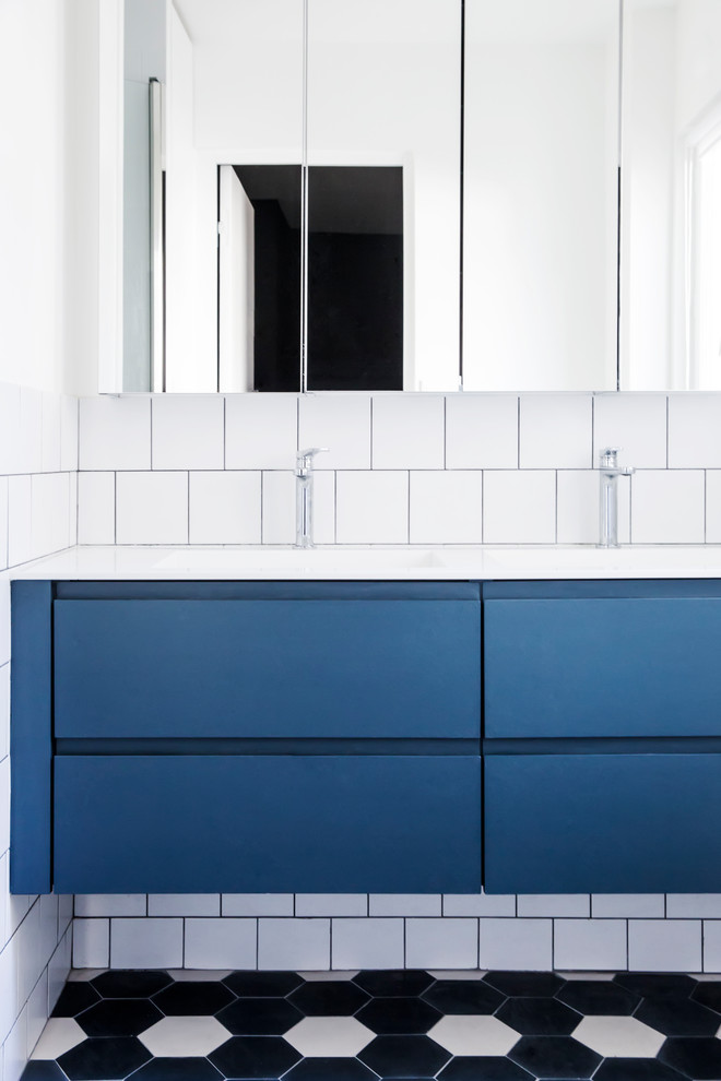 На фото: ванная комната в современном стиле с плоскими фасадами, синими фасадами, белой плиткой, белыми стенами, консольной раковиной, синим полом и белой столешницей с