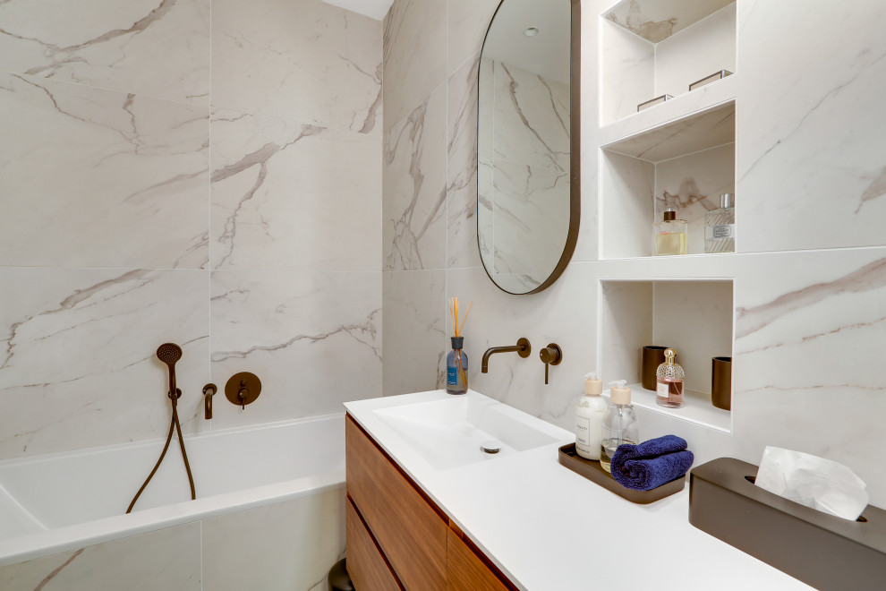 Immagine di una stanza da bagno design con ante lisce, ante in legno scuro, vasca ad alcova, piastrelle grigie, lavabo integrato, top bianco e un lavabo