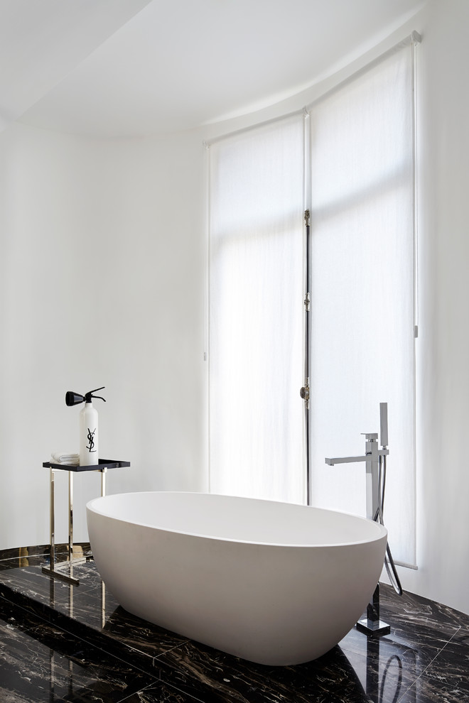 Cette photo montre une grande salle de bain tendance pour enfant avec une baignoire posée, un carrelage blanc, un mur blanc, un sol en marbre et un sol noir.