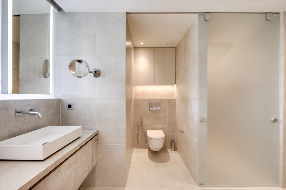 Свежая идея для дизайна: большая главная ванная комната в стиле неоклассика (современная классика) с плоскими фасадами, серыми фасадами, накладной ванной, душем в нише, инсталляцией, серой плиткой, керамической плиткой, серыми стенами, полом из керамической плитки, настольной раковиной, столешницей из бетона, серым полом, душем с раздвижными дверями и серой столешницей - отличное фото интерьера