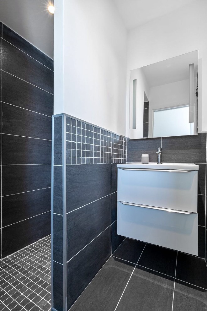 Bild på ett litet funkis vit vitt en-suite badrum, med öppna hyllor, vita skåp, en kantlös dusch, svart kakel, keramikplattor, vita väggar, klinkergolv i keramik, ett konsol handfat, bänkskiva i akrylsten, svart golv och med dusch som är öppen