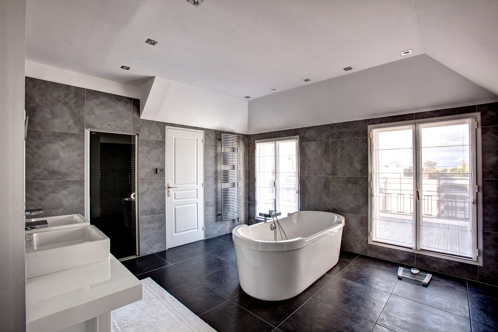 Inspiration för stora moderna en-suite badrum, med ett väggmonterat handfat, ett fristående badkar, grå kakel, grå väggar, vita skåp och en dusch i en alkov
