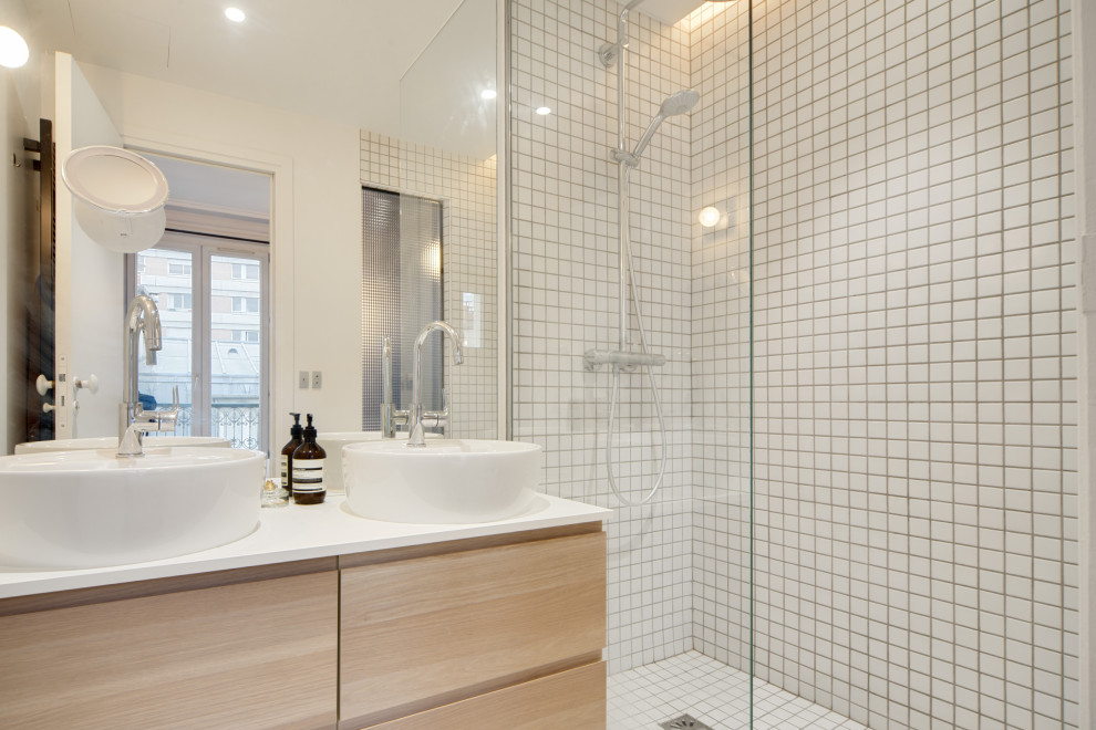 Bild på ett litet funkis vit vitt badrum med dusch, med luckor med profilerade fronter, skåp i ljust trä, en kantlös dusch, vit kakel, porslinskakel, vita väggar, betonggolv, ett nedsänkt handfat, laminatbänkskiva och grått golv