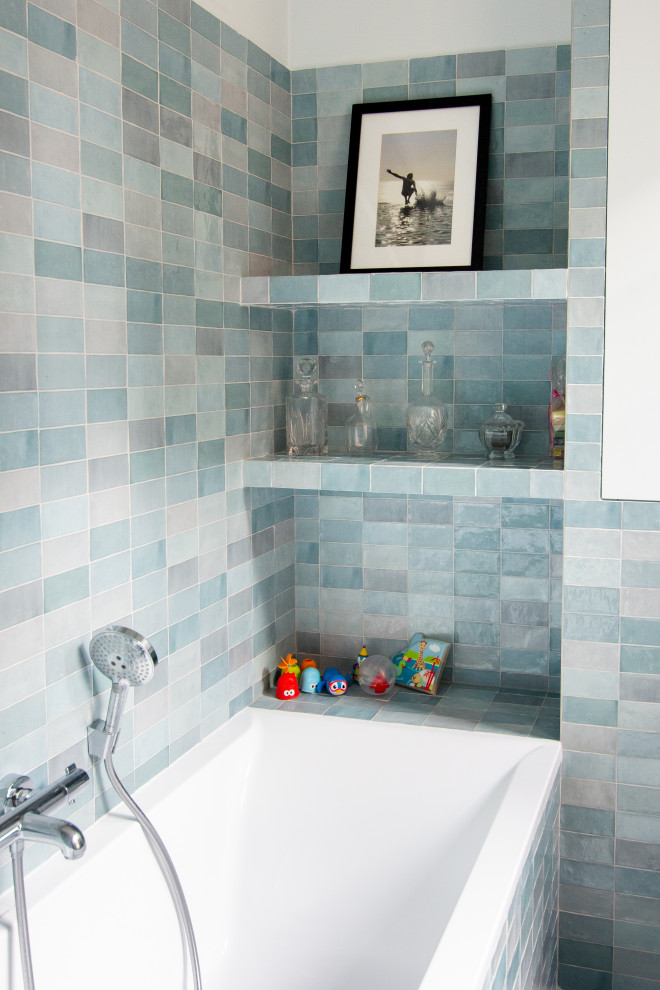 Inredning av ett mellanstort blå blått en-suite badrum, med blå skåp, ett undermonterat badkar, en vägghängd toalettstol, blå kakel, keramikplattor, blå väggar, ett nedsänkt handfat, kaklad bänkskiva och beiget golv