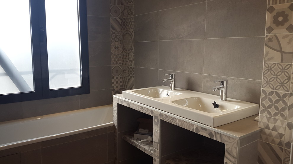 Modern inredning av ett mellanstort grå grått en-suite badrum, med öppna hyllor, vita skåp, ett hörnbadkar, våtrum, grå kakel, cementkakel, grå väggar, ett avlångt handfat, bänkskiva i akrylsten och med dusch som är öppen