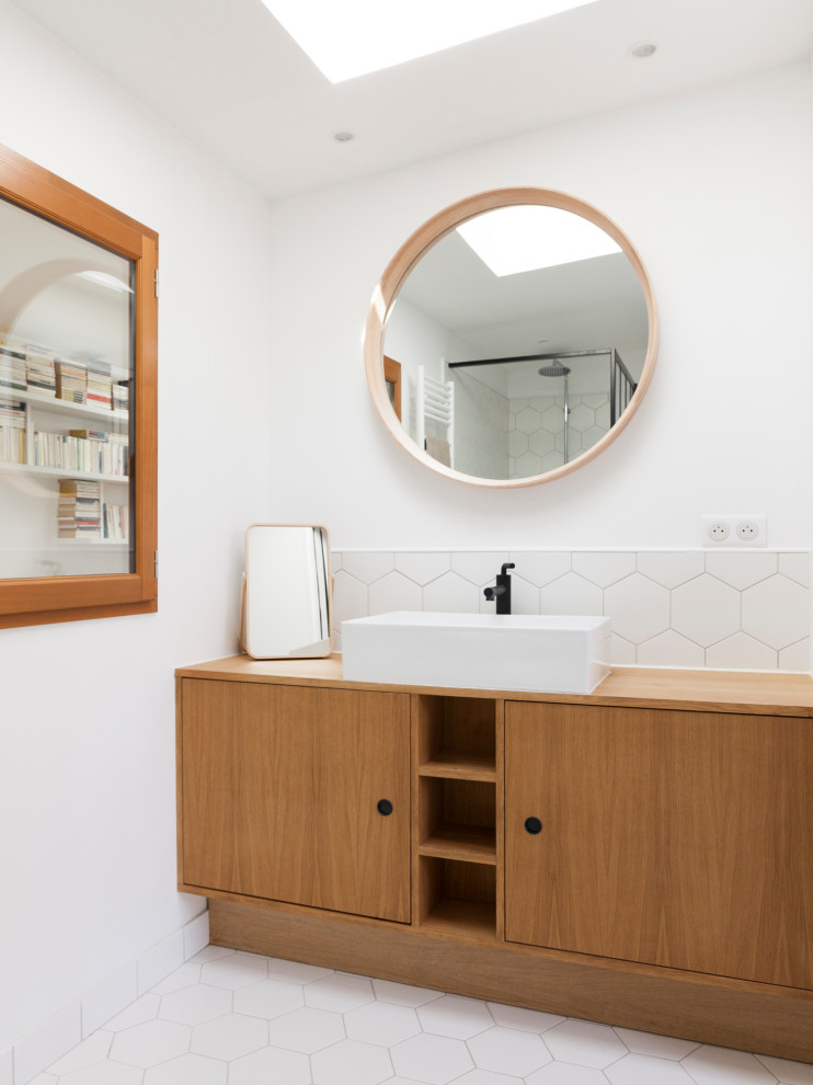 パリにあるコンテンポラリースタイルのおしゃれな浴室 (フラットパネル扉のキャビネット、中間色木目調キャビネット、白いタイル、白い壁、ベッセル式洗面器、木製洗面台、白い床、洗面台1つ、オープン型シャワー、壁掛け式トイレ、セラミックタイル、セラミックタイルの床、白い洗面カウンター、独立型洗面台) の写真