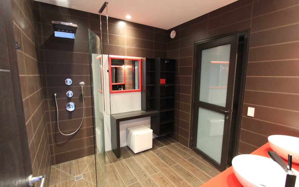 Diseño de cuarto de baño principal contemporáneo de tamaño medio con armarios abiertos, puertas de armario negras, ducha a ras de suelo, paredes marrones, lavabo encastrado, encimera de vidrio y suelo marrón