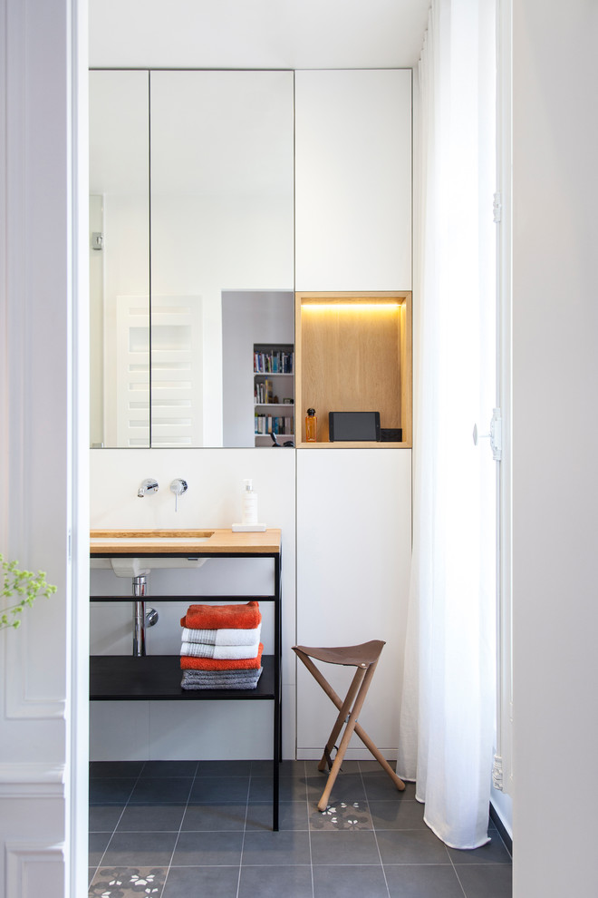 Photo of a contemporary bathroom in Paris with flat-panel cabinets, white cabinets, white walls, cement flooring, a submerged sink and grey floors.