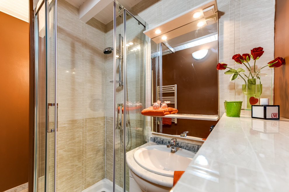 Modern inredning av ett litet badrum med dusch, med en hörndusch, en toalettstol med hel cisternkåpa, beige kakel, keramikplattor, bruna väggar, klinkergolv i keramik, ett undermonterad handfat, marmorbänkskiva, beiget golv och dusch med skjutdörr