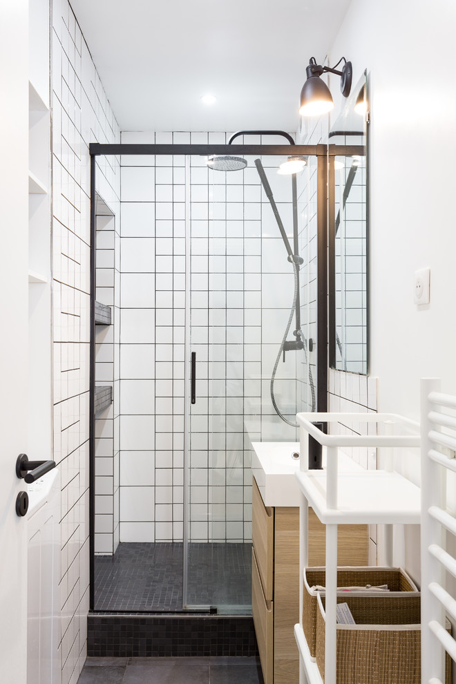 Cette photo montre une salle de bain scandinave en bois clair avec un placard à porte plane, un carrelage blanc, des carreaux de céramique, un mur blanc, un lavabo suspendu, un sol gris et une cabine de douche à porte coulissante.