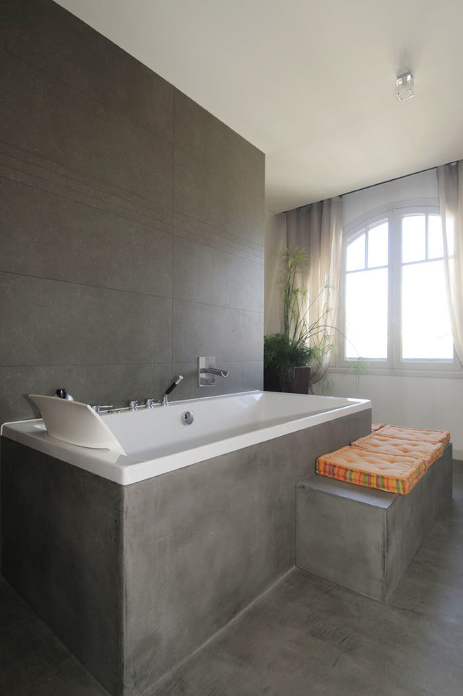 Idée de décoration pour une grande salle de bain principale design avec un bain bouillonnant, un carrelage gris, des carreaux de céramique, sol en béton ciré et un sol gris.