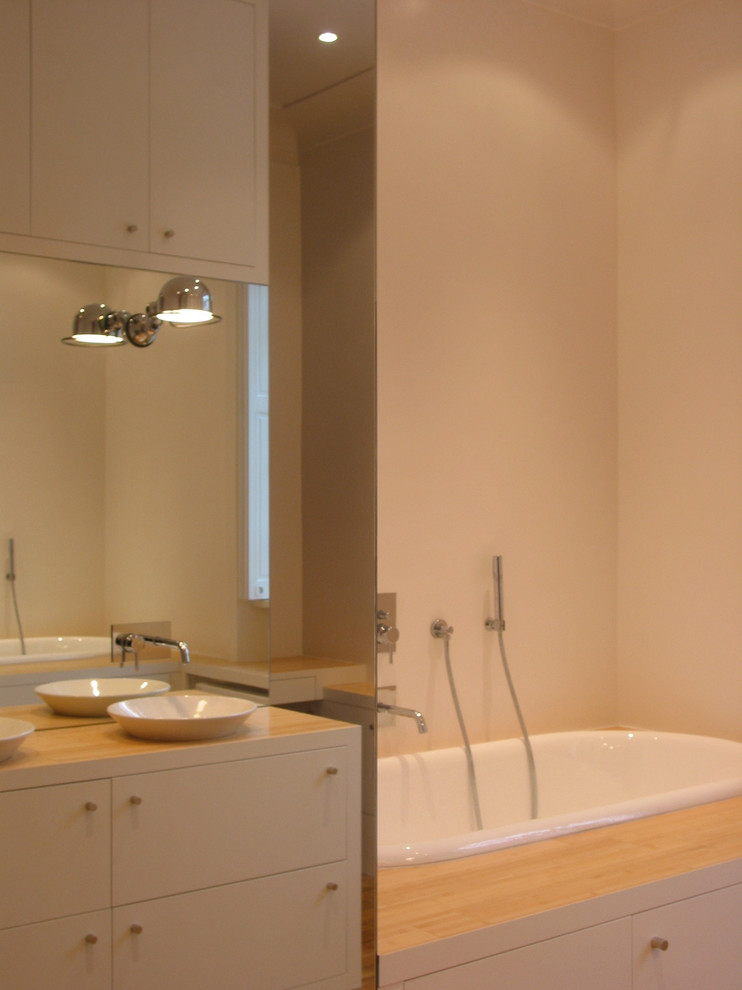 Стильный дизайн: большая главная ванная комната в современном стиле с полновстраиваемой ванной, душем без бортиков, красной плиткой, зеркальной плиткой, настольной раковиной, столешницей из дерева, душем с распашными дверями, белыми стенами, полом из бамбука и бежевым полом - последний тренд