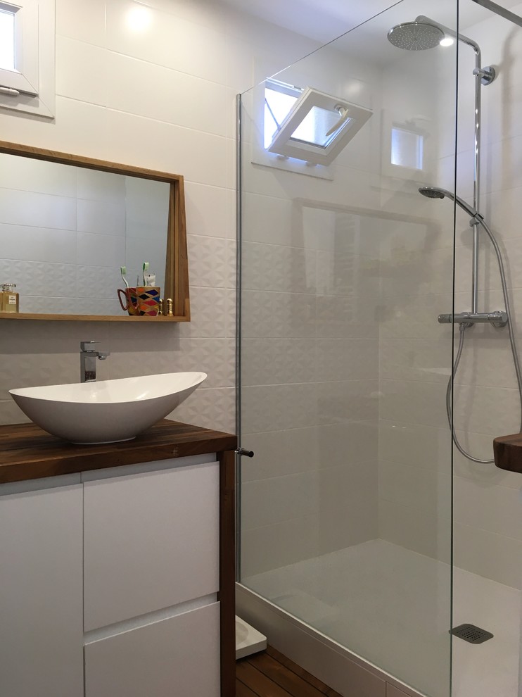 Aménagement d'une douche en alcôve contemporaine avec un placard à porte affleurante, des portes de placard blanches, un carrelage blanc, un mur blanc, un sol en bois brun, un lavabo posé et un plan de toilette en bois.
