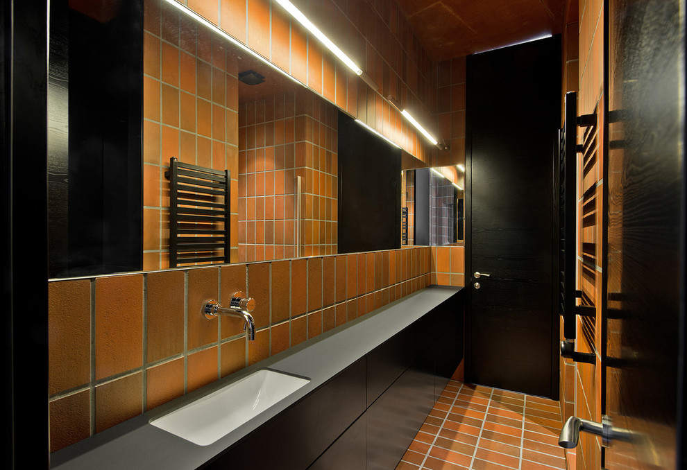 Idéer för industriella badrum, med brun kakel, stickkakel, bruna väggar, tegelgolv, ett undermonterad handfat och brunt golv