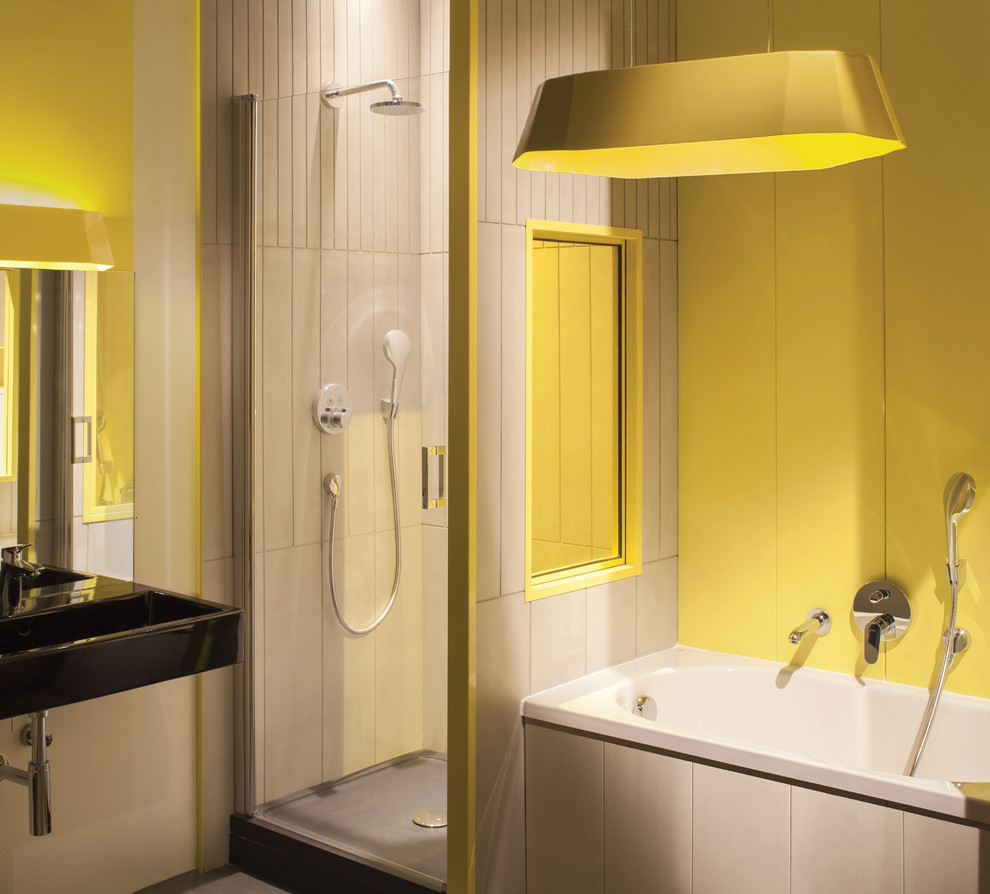 Ispirazione per una stanza da bagno padronale contemporanea di medie dimensioni con WC sospeso, vasca da incasso, pareti gialle e lavabo sospeso