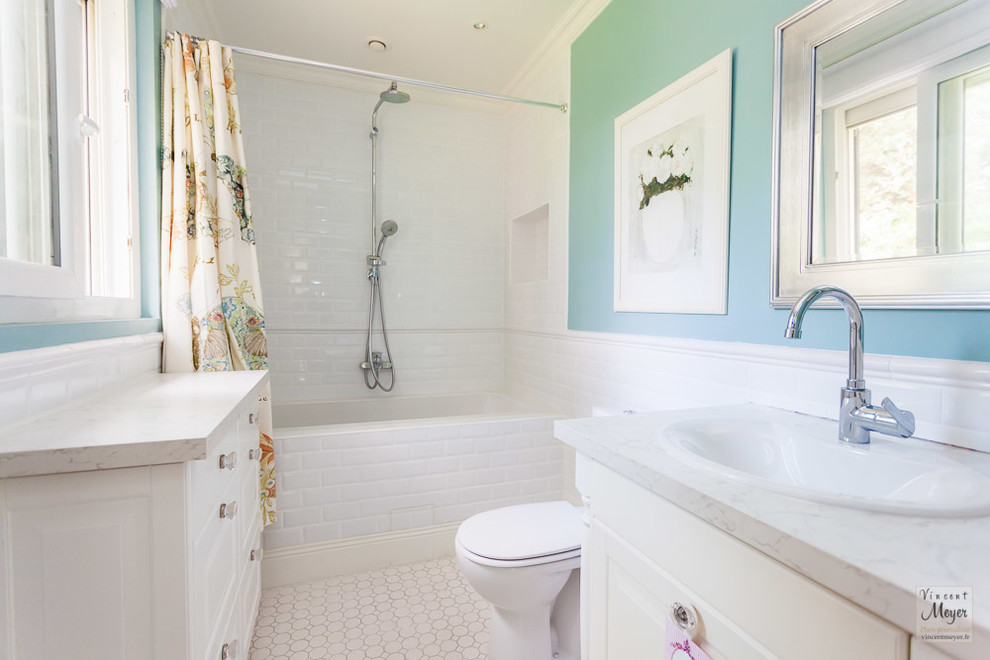 Inspiration pour une salle d'eau minimaliste de taille moyenne avec un placard sans porte, une baignoire encastrée, WC à poser, un carrelage blanc, des carreaux de porcelaine, un mur bleu, un sol en carrelage de porcelaine et un plan de toilette en carrelage.