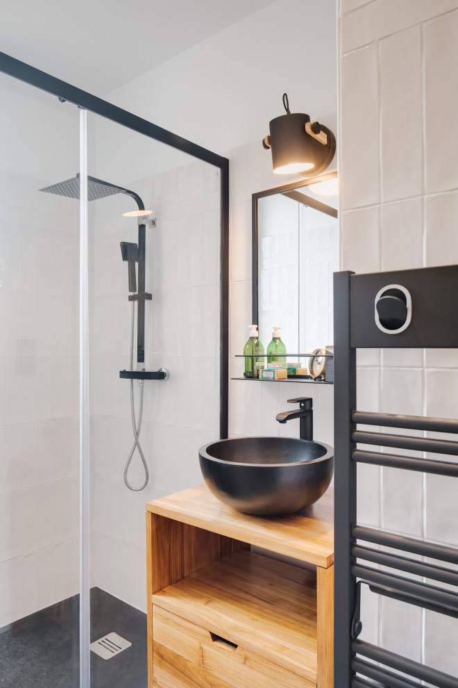 Inspiration for a small contemporary bathroom in Paris with open cabinets, medium wood cabinets, an alcove shower, white tiles, white walls, a vessel sink, wooden worktops, black floors, brown worktops and a single sink.