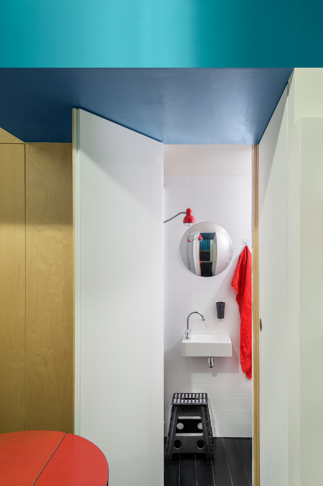 Aménagement d'une petite salle de bain contemporaine avec un lavabo suspendu, un carrelage blanc, un mur blanc et un sol noir.