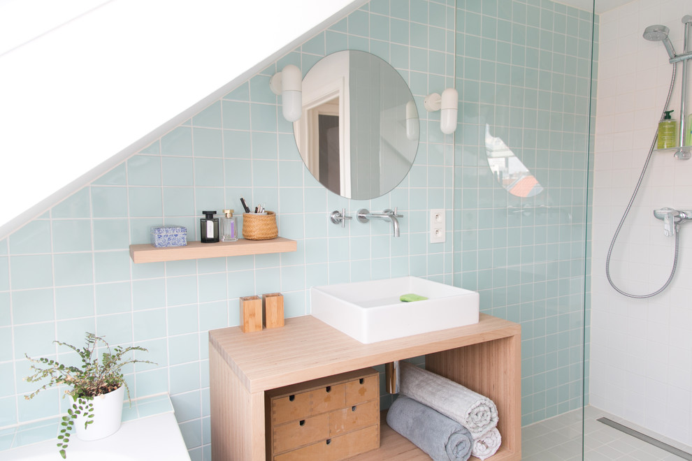 Пример оригинального дизайна: маленькая ванная комната в скандинавском стиле с открытыми фасадами, светлыми деревянными фасадами, полновстраиваемой ванной, душем без бортиков, синей плиткой, керамической плиткой, белыми стенами, полом из бамбука, душевой кабиной, консольной раковиной, столешницей из плитки, коричневым полом, душем с раздвижными дверями и синей столешницей для на участке и в саду