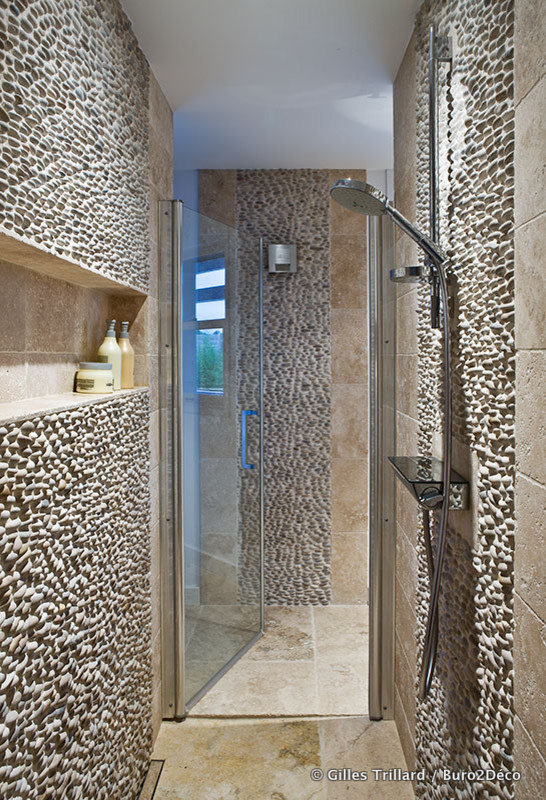 Inredning av ett eklektiskt mellanstort badrum med dusch, med beige kakel, stenkakel, beige väggar, kalkstensgolv, luckor med lamellpanel, skåp i slitet trä, en kantlös dusch, bänkskiva i kalksten, beiget golv, en toalettstol med separat cisternkåpa och ett undermonterad handfat