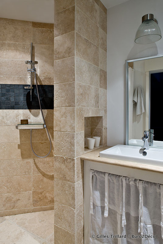 Idéer för ett mellanstort eklektiskt badrum med dusch, med öppna hyllor, en kantlös dusch, stenkakel, beige väggar, kalkstensgolv, bänkskiva i kalksten, ett nedsänkt handfat, vita skåp, en vägghängd toalettstol, flerfärgad kakel och beiget golv
