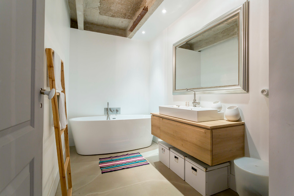 Modernes Badezimmer mit Aufsatzwaschbecken, flächenbündigen Schrankfronten, hellbraunen Holzschränken, freistehender Badewanne und weißer Wandfarbe in Paris