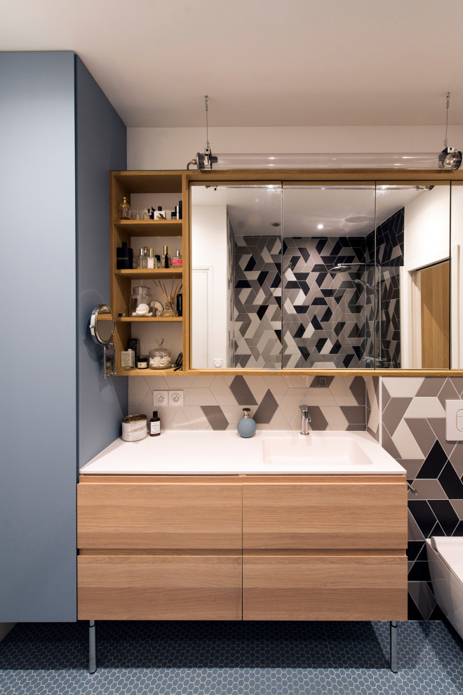 Idée de décoration pour une salle d'eau design en bois clair de taille moyenne avec un placard à porte plane, un carrelage noir, un carrelage gris, un carrelage blanc, des carreaux de porcelaine, un mur gris, un sol en carrelage de porcelaine, un lavabo intégré, un sol gris, un plan de toilette blanc, meuble double vasque et meuble-lavabo sur pied.