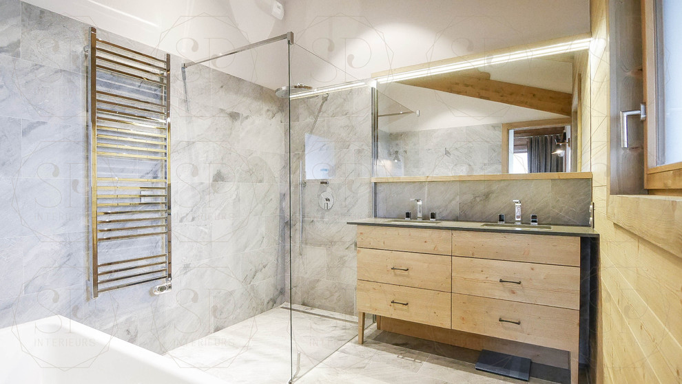 Réalisation d'une grande salle de bain principale chalet avec une baignoire d'angle, une douche d'angle, du carrelage en marbre, un sol en carrelage de céramique, un sol gris et une cabine de douche à porte battante.