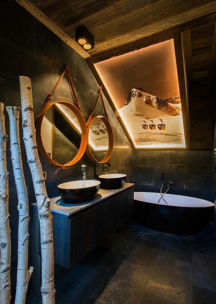 На фото: главная ванная комната среднего размера в стиле рустика с черными фасадами, отдельно стоящей ванной, черной плиткой, черными стенами, настольной раковиной и зеркалом с подсветкой